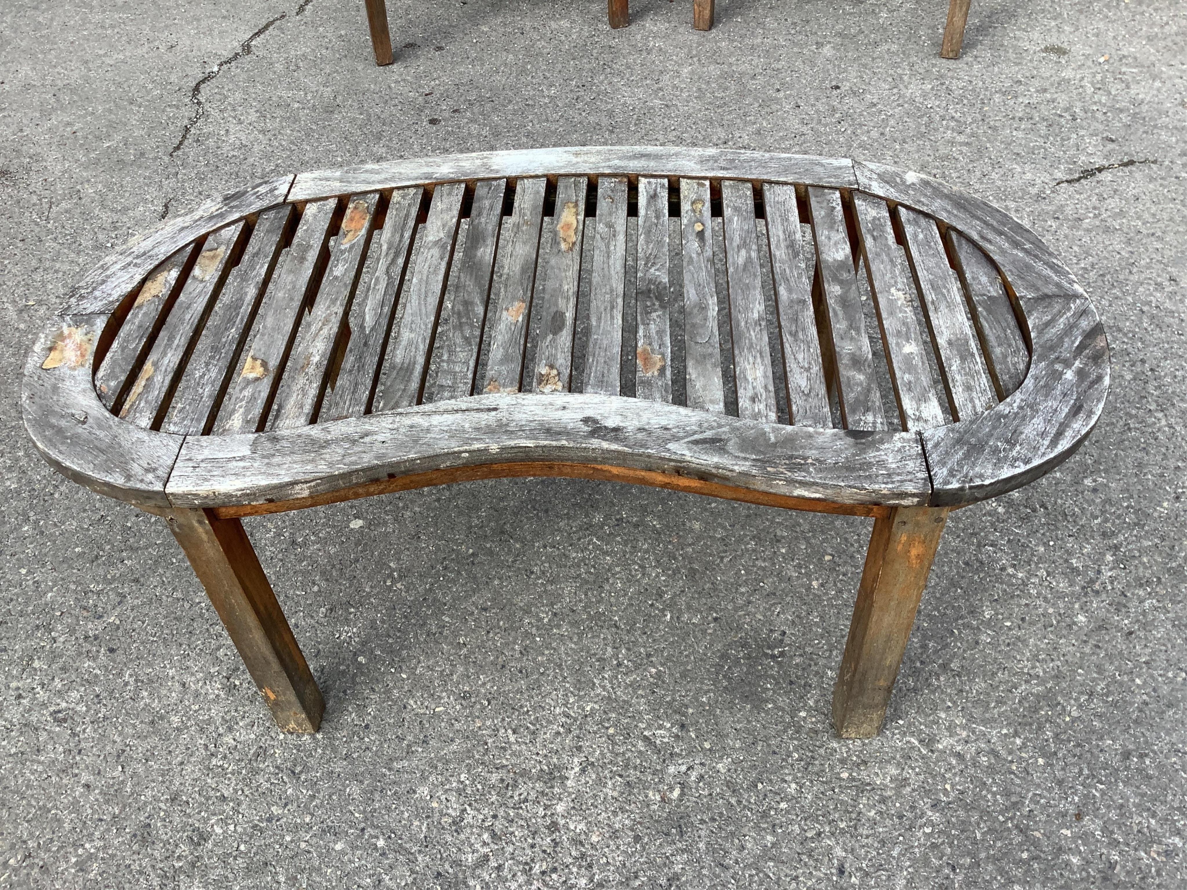 A weathered teak garden 'banana' bench, width 150cm, depth 60cm, height 84cm, a pair of chairs and coffee table